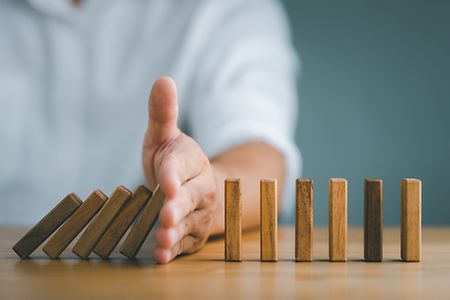 Hand,Stopping,The,Domino,Business,Crisis,Effect,Or,Risk,Protection