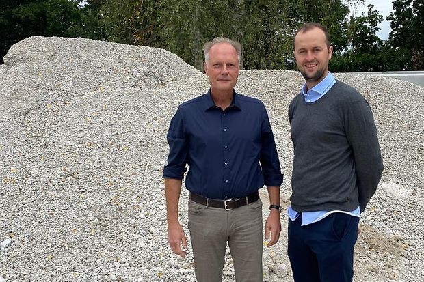 Volker Witt und Lorenz K&auml;hler stehen vor einem Kiesberg.