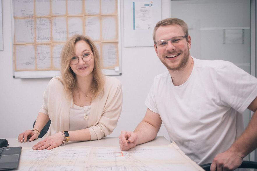 Karoline und Nils Eckhoff an Tisch mit Plan, l&auml;cheln in Kamera.
