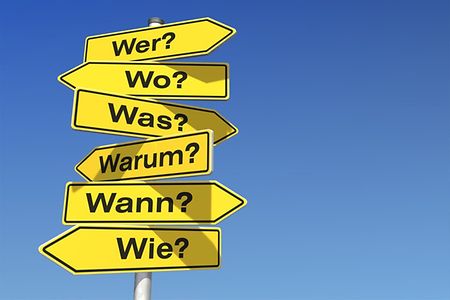 W-Fragen als gelbe Stra&szlig;enschilder vor blauem Himmel