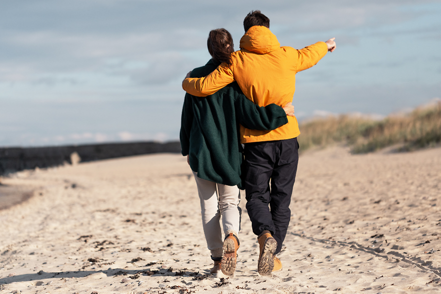 P&auml;rchen in warmen Klamotten spaziert am Strand