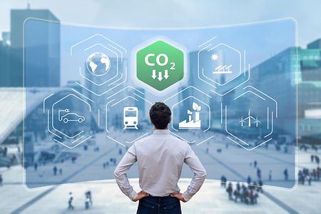 Mann blickt auf digitale Tafel mit CO2-Symbolen