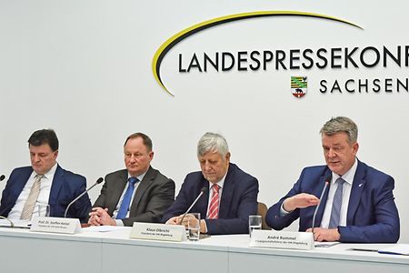 Vier Personen sitzen an einem Konferenztisch.