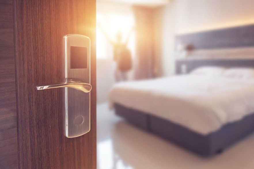 Der Blick geht durch eine offene T&uuml;r in ein sonnendurchflutetes Hotelzimmer.