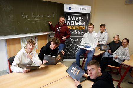 Mehrer Jugendliche und ein Herr befinden sich in einem Klassenraum.