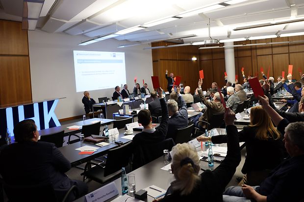 Mitglieder der Vollversammlung sitzen im Sitzungssaal und stimmen ab