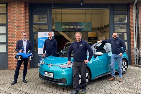 Die Gr&uuml;nder mit Wirtschaftsminister Claus Ruhe Madsen vor einem E-Auto