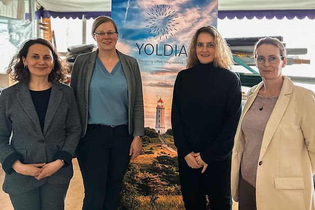 Vier Frauen vor einem Banner mit Yoldia-Aufschrift