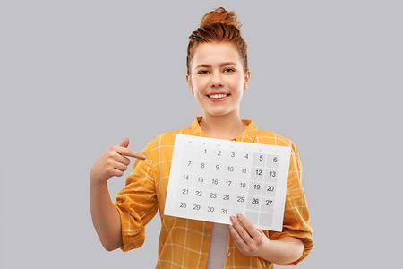 happy red haired teenage girl with calendar sheet