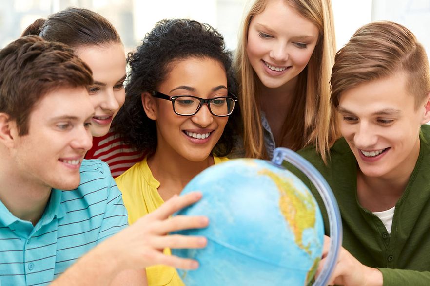 happy high school students looking at earth globe