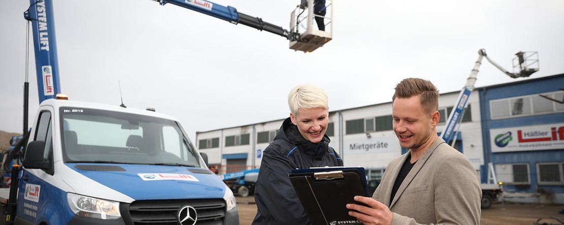 Zwei Personen stehen vor einen Hebeb&uuml;hne und sprechen miteinander