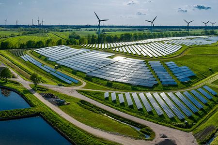 Solaranlage im Sonnenschein, im Hintergrund Felder und Windr&auml;der