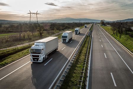 LKW-Kolonne auf einer Landstra&szlig;e.