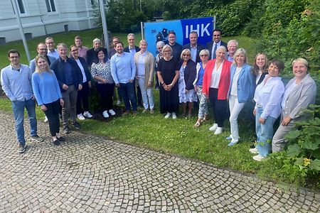 Eine Gruppe mit Frauen und M&auml;nnern stehen nebeneinander und schauen Richtung Fotograf.