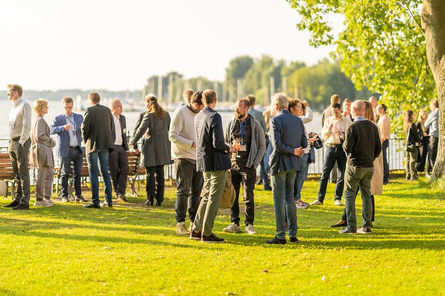 Unternehmer vernetzen sich bei sommerlichem Wetter an einem See.