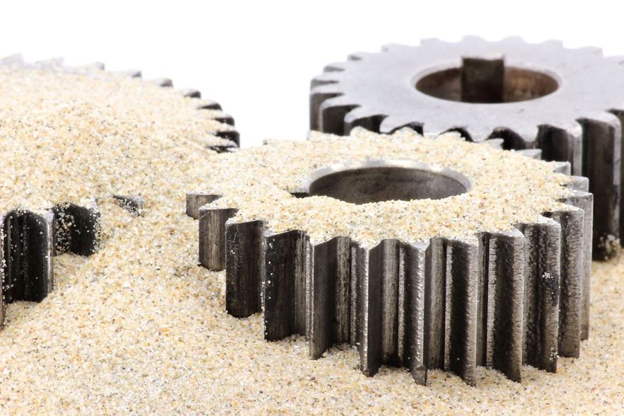 Drei Zahnr&auml;der mit Sand bedeckt