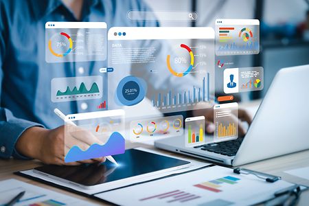 Symbolfoto: Mann tippt auf Notebook im Vordergrund sind Symbole zu statistischen Daten zu sehen