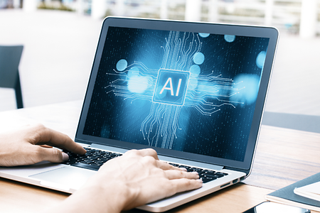 H&auml;nde eine Mannes ber&uuml;hren die Tastatur eines Laptops. Auf dem Bild steht: AI (K&uuml;nstliche Intelligenz)