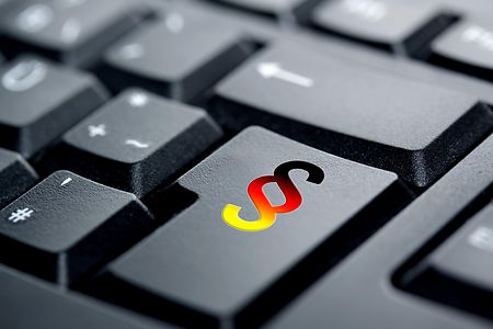Schwarz-rot-goldenes Paragrafensymbol auf einer PC-Tastatur.