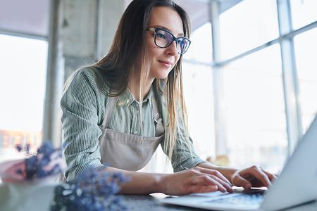 Eine Frau mit Brille sitzt vor einem Laptop