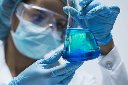 Researcher watching chemical reaction after adding test material into flask