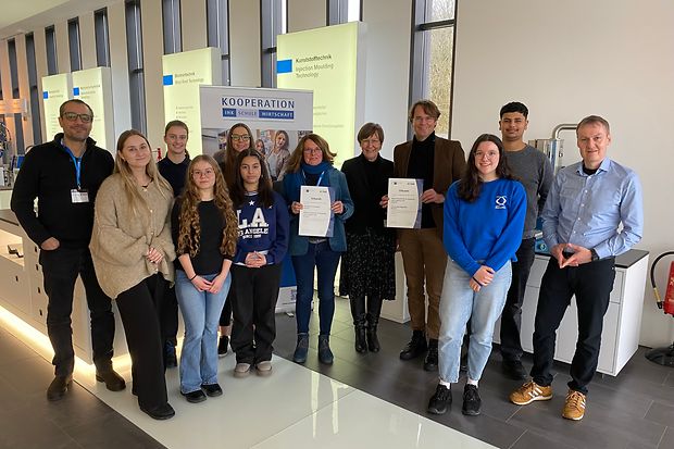 Vertreter von IHK, Schule und Unternehmen halten die Kooperationsvereinbarung in die Kamera.