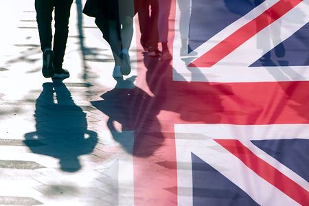 Silhouetten gehender Menschen &uuml;berlagert von der britischen Flagge.