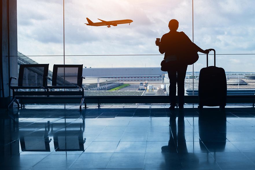 Reisende am Flughafen mit Blick auf startendes Flugzeug.