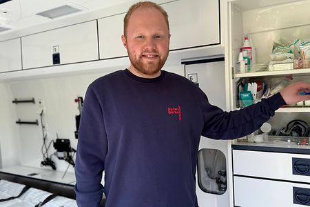 Mann im Rettungswagen greift nach Vorr&auml;ten in einem offenen Schrank.