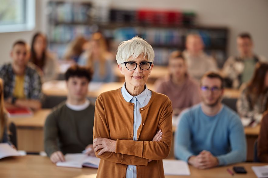 Senior female teacher in front of her students in the classroom.