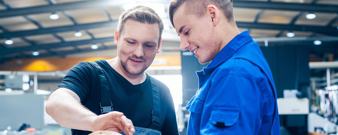 Master discussing a workpiece with his apprentice or trainee