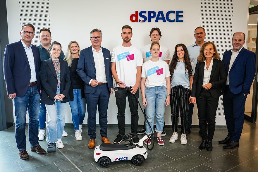 Unternehmensbesuch bei dSPACE mit jungen Mitarbeitenden und Mini-Elektrofahrzeug.
