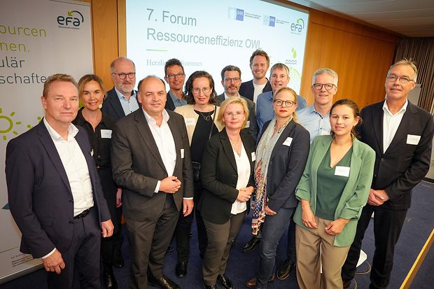 Gruppenbild vom 7. Forum Ressourceneffizienz OWL vor Pr&auml;sentationswand