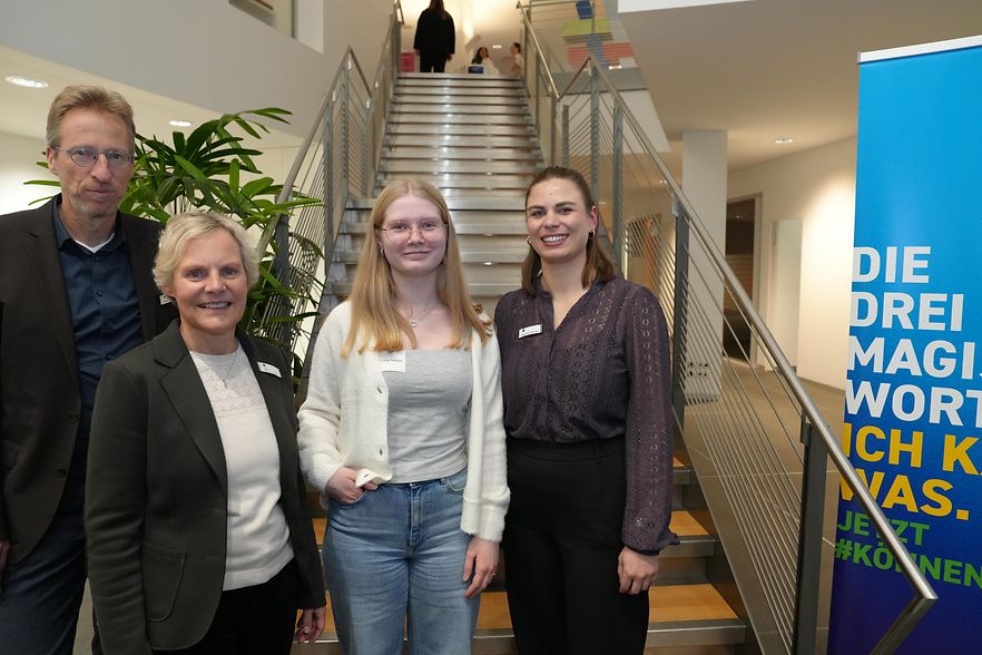 Gruppenfoto: Drei IHK-Vertreter stehen mit einer Ausbildungsbotschafterin aus dem Kreis Herford auf einer Treppe