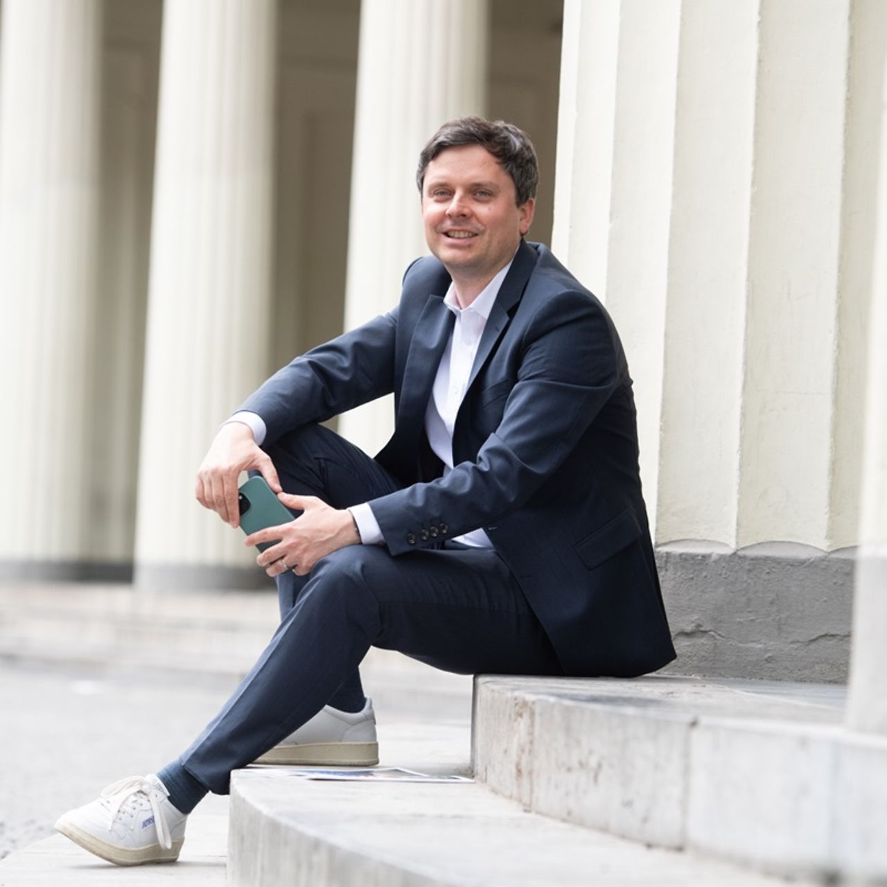 Ein junger Mann in Businesskleidung sitzt auf einer Steintreppe
