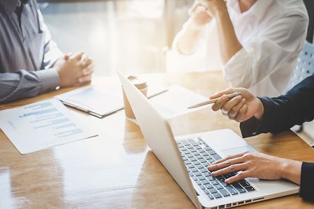 Gesch&auml;ftstreffen mit Laptop, Charts und Diskussion &uuml;ber Strategien.