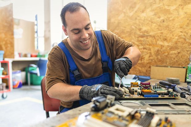 Mitarbeiter eines Recyclingunternehmens zerlegt einen ausrangierten Rechner