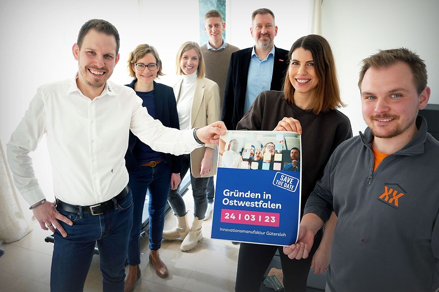 Sieben Personen halten ein Poster zur Veranstaltung &bdquo;Gr&uuml;nden in Ostwestfalen&ldquo;.