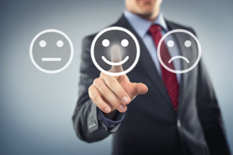Gesch&auml;ftsmann dr&uuml;ckt auf einen von drei Smiley-Buttons und w&auml;hlt dabei einen l&auml;chelnden Smiley