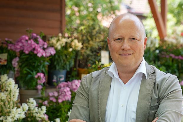  Peter Zens, Inhaber des Erlebnisbauernhofs Getrudenhof, steht vor bunten Blumen. 