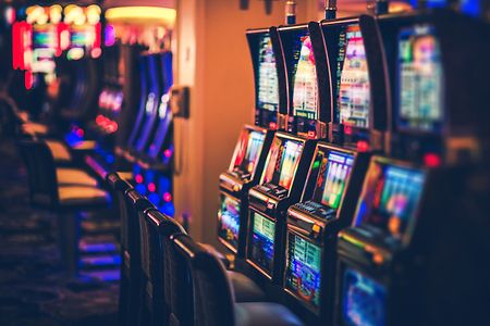 Reihe von leuchtenden Spielautomaten in einem Casino.