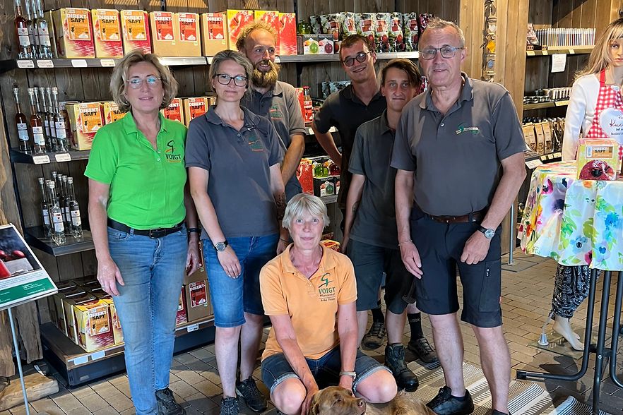 Das Team von Pflanzen Voigt in Priorau steht im Laden vor Regalen mit lokalen Delikatessen