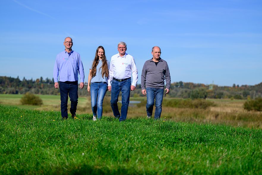 Karsten Jenkel mit drei Mitarbeitenden auf Wiese