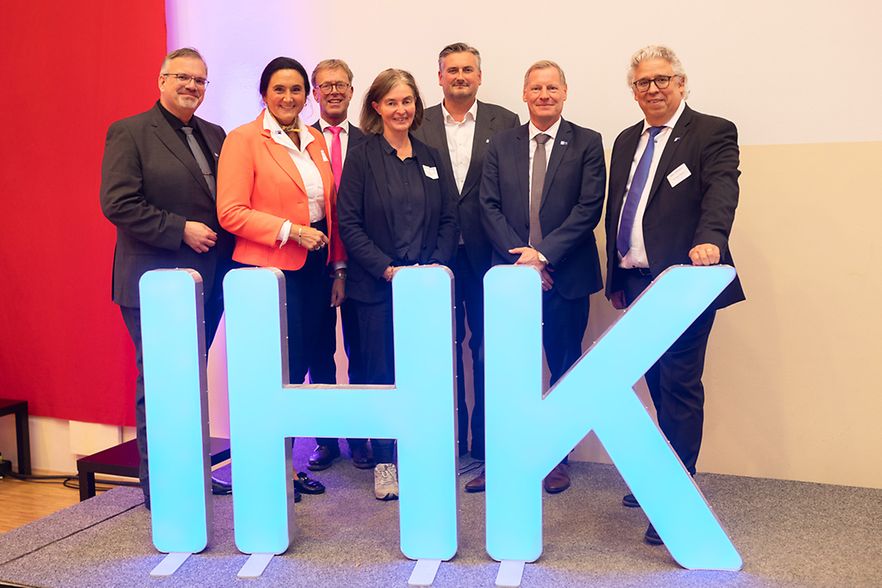 Eine Gruppe Menschen hinter den drei IHK-Buchstaben