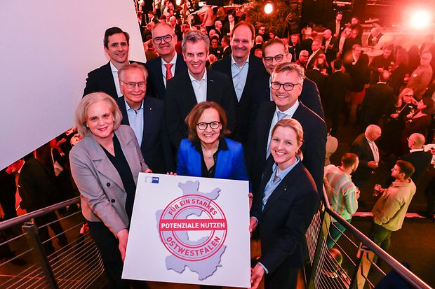 Gruppenfoto von Wirtschaftsvertreterinnen und -vertretern, die gemeinsam ein Schild mit einer Ostwestfalen-Grafik halten