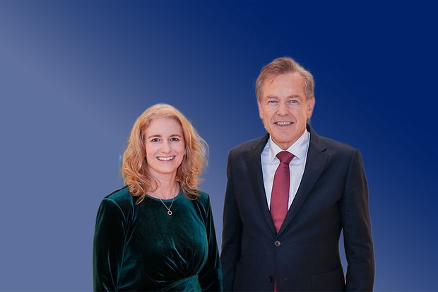 Nicole Grünewald und Uwe Vetterlein stehen vor blauem Hintergrund