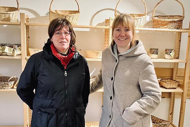 Zwei Frauen stehen vor einem leeren Regal und schauen in die Kamera.