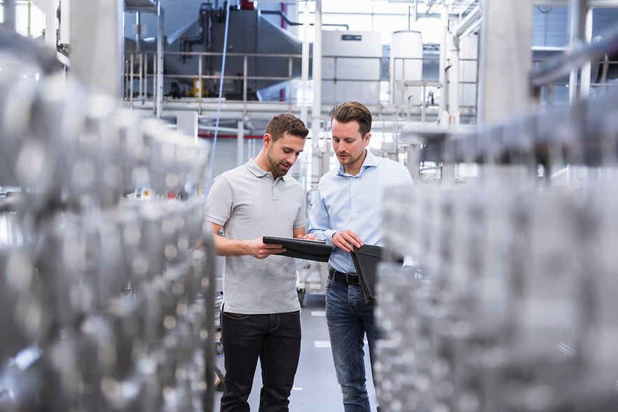Two men with tablet talking in factory shop floor