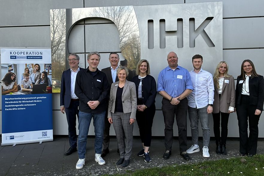 Gruppe mit neun Personen posiert vor IHK-Logo