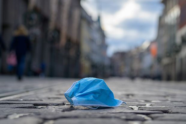 Weggeworfene Corona-Maske auf Kopfsteinpflaster in einer Stadt